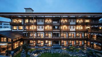 A multi-story hotel with traditional architecture, featuring balconies and a courtyard with a water feature.