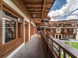 Varanda de madeira com vista para um pátio e edifícios vizinhos.