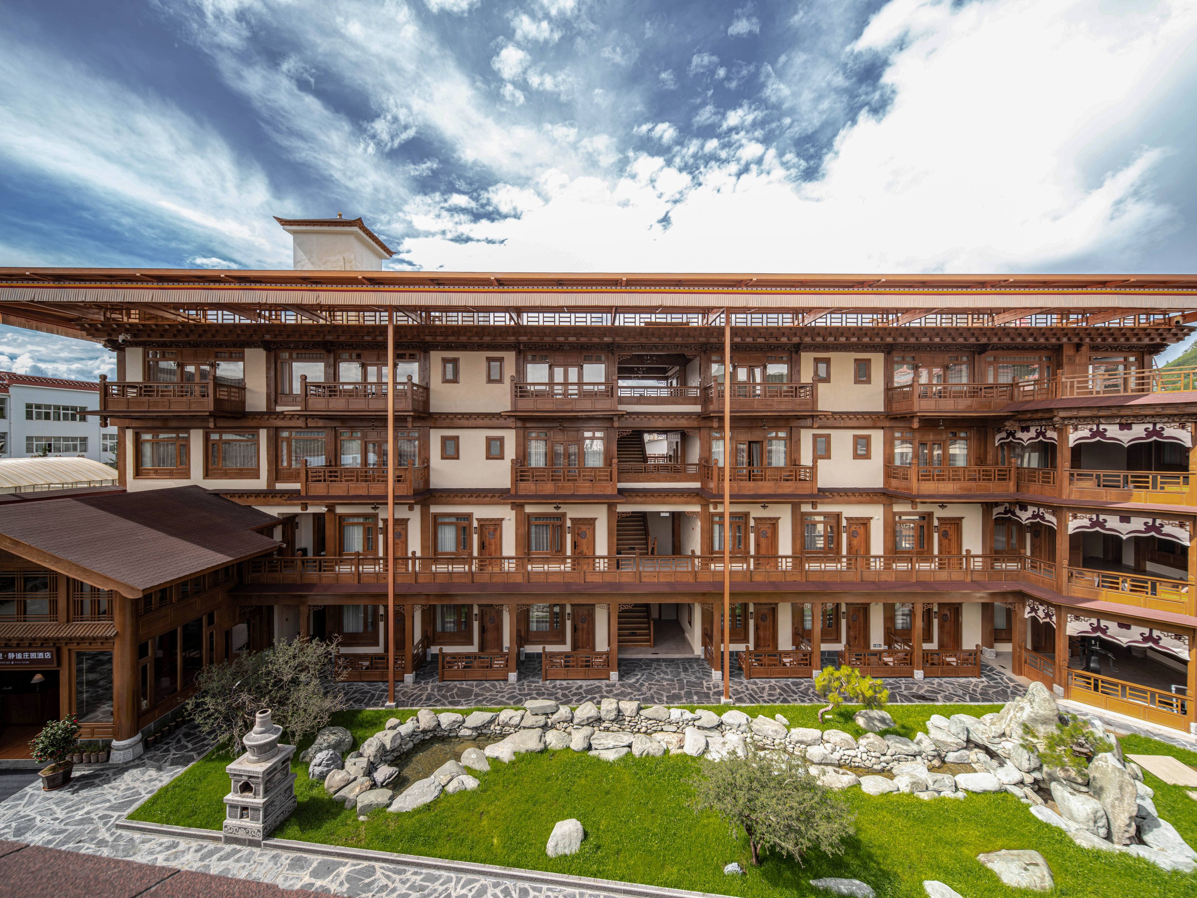 Un edificio de varios pisos con balcones, un patio de piedra y un estilo arquitectónico tradicional.