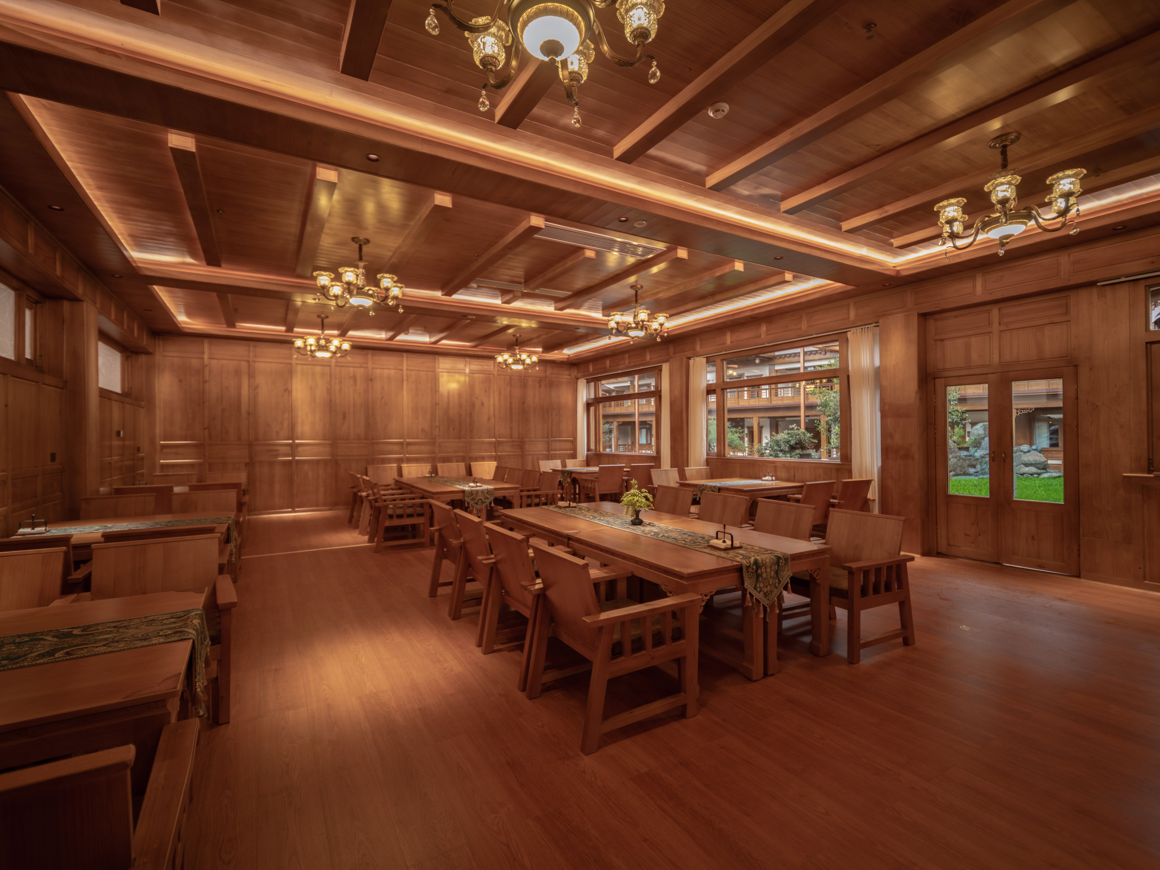 A spacious room with wooden paneling, large windows, and multiple chandeliers.