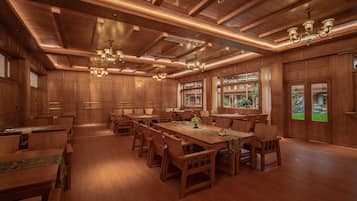 A spacious room with wooden paneling, large windows, and multiple chandeliers.