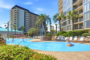 A hotel pool area with a clear blue pool, lounge chairs, palm trees, and a modern building with balconies. - 🏝️ Windward 108 🌊 Beach Front 🏖️ Pools 🏊 Snowbird Friendly ☀️ (Panama City Beach)