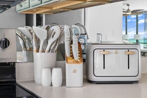 A kitchen with a white toaster, a container of utensils, and salt and pepper shakers. - 🏝️ Windward 108 🌊 Beach Front 🏖️ Pools 🏊 Snowbird Friendly ☀️ (Panama City Beach)