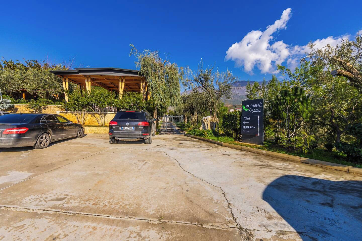 A parking area with a sign for 'Muraga Villas' indicating the entrance and reception.