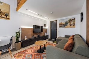 Una sala de estar moderna con un sofá, una mesa de centro, un televisor y una alfombra estampada.