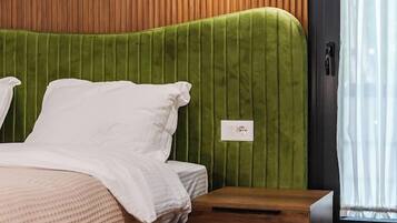 Una camera da letto con una testiera imbottita verde, un comodino in legno e un tappeto decorato.