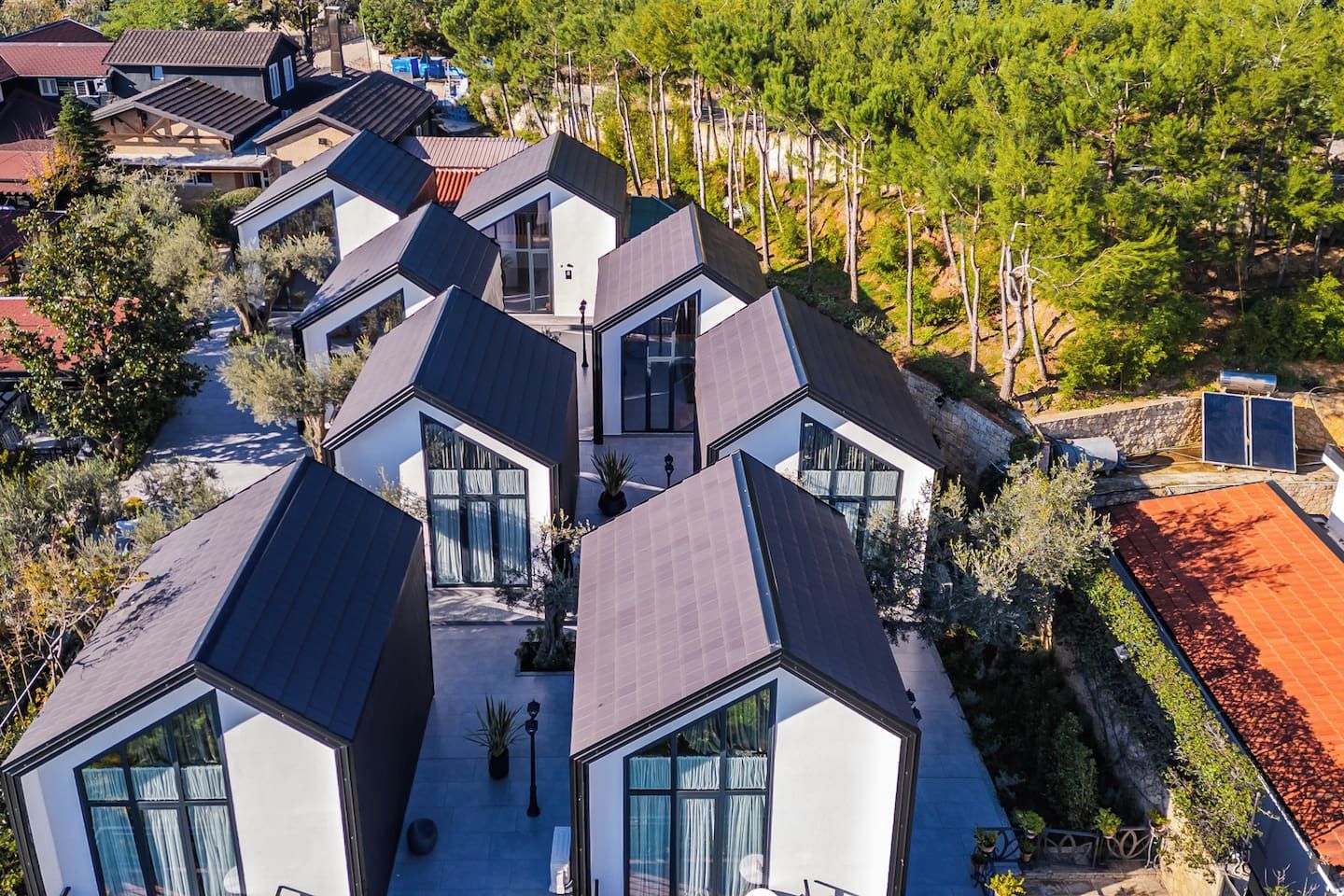 A modern residential area with multiple houses featuring geometric roofs and large windows.