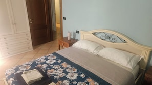 A bedroom with a bed, a nightstand, a lamp, a dresser, and a door. - Luna Blu Country House - Primaluna Farm (Emilia-Romagna)