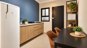 A modern kitchen with a refrigerator, stove, and sink. There is a dining table with chairs and a potted plant on the table. - STUDIO 05 (Vinhedo)