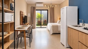 A compact hotel room with a kitchenette, a dining area, and a bed with a view of the outdoors. - STUDIO 05 (Vinhedo)