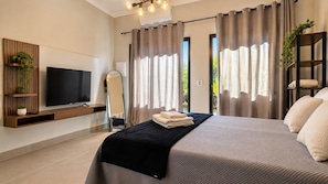 A modern bedroom with a bed, a TV, a mirror, and a plant. - STUDIO 05 (Vinhedo)