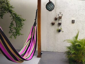 A hammock hanging from a wooden post, a textured wall, and several potted plants. - Alma Zen House - Comfort and beach (180m) Air Conditioning/Heated Pool (Guaratuba)