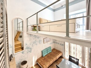 Une pièce à plusieurs niveaux comprenant un escalier, un canapé, une table à manger et un coin cuisine.
