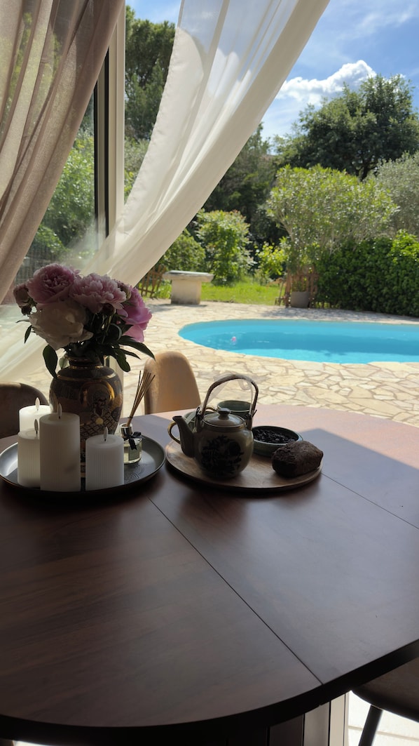A table with a vase of flowers, candles, a teapot, and a tray with a cookie. - A house in a quiet location in Provence with a pool, BBQ, and bike paths—pets welcome 🐾🚲🌿 (Loriol-du-Comtat)