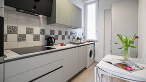 Een moderne keuken met een inbouwvaatwasser, een koffiezetapparaat en een raam dat voor natuurlijk licht zorgt.
