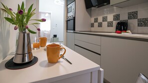 Eine moderne Küche mit einer weißen Arbeitsplatte, einer Edelstahl-Kaffeemaschine und einer Vase mit violetten Tulpen.