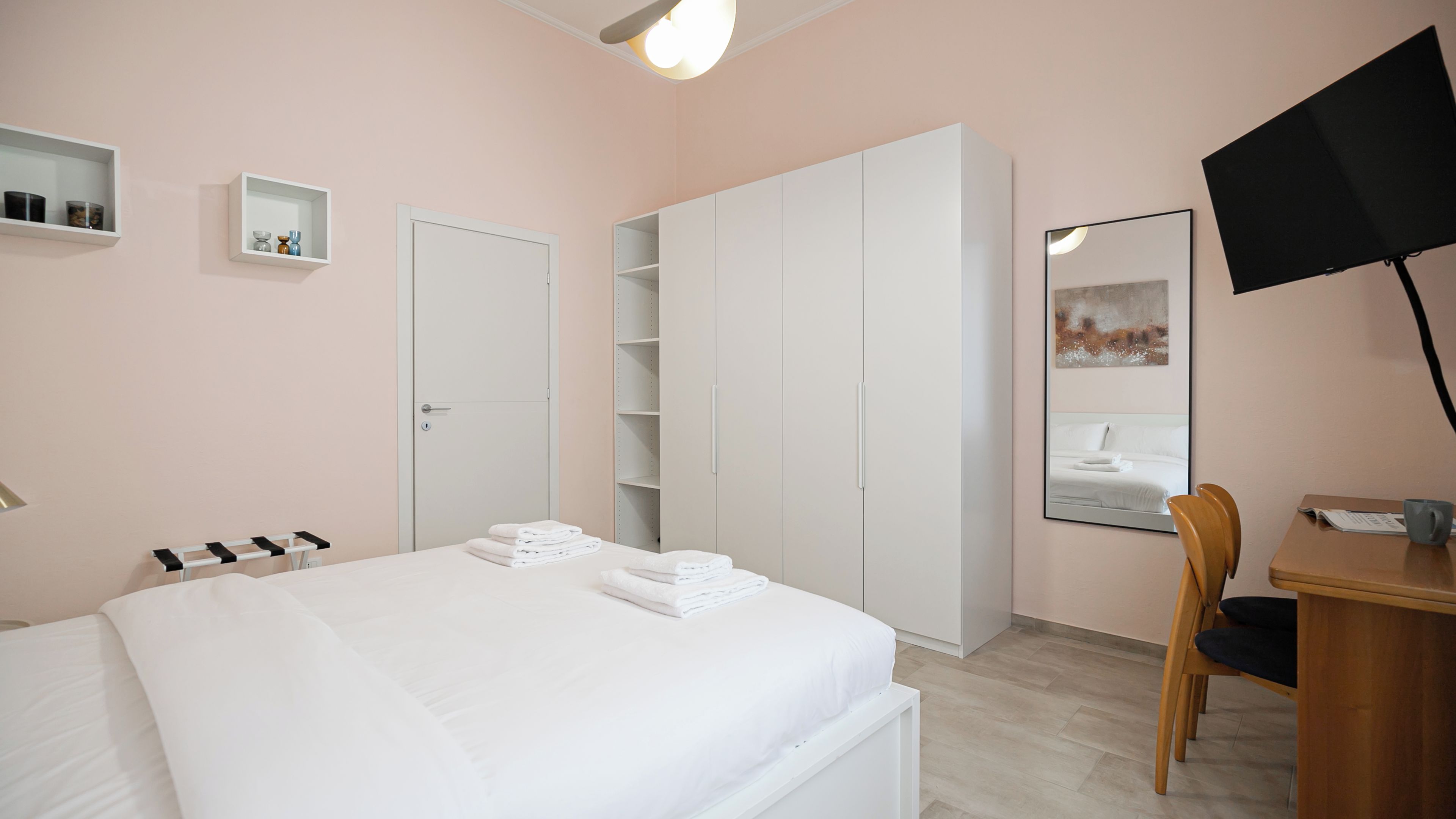 Ein Schlafzimmer mit Bett, Schreibtisch, Stuhl, Kleiderschrank und Fernseher.