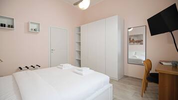 Ein Schlafzimmer mit Bett, Schreibtisch, Stuhl, Kleiderschrank und Fernseher.