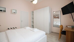 Ein Schlafzimmer mit Bett, Schreibtisch, Stuhl, Kleiderschrank und Fernseher.