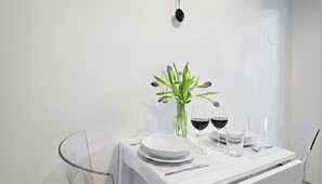 Een minimalistisch gedekte tafel met een witte tafel, glazen servies en een vaas met bloemen.