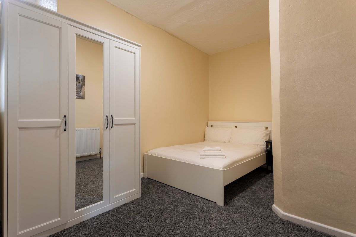 A bedroom with a bed, a wardrobe, and a radiator.