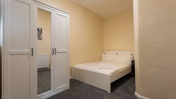 A bedroom with a bed, a wardrobe, and a radiator.