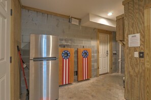 Un pasillo con un refrigerador de acero inoxidable, dos puertas de madera con diseños de la bandera estadounidense y una puerta de madera con un letrero.