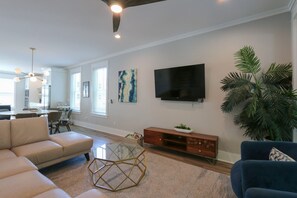 Una sala moderna con sofá, mesa de centro, televisor y planta.