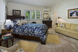 A bedroom with a bed, a sofa, a nightstand, a lamp, a window, and a door. - Exquisite, private villa, centrally located and close to world-famous Magen`s Bay! (St. Thomas)