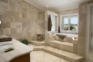 Un baño con suelo de mármol, bañera, zona de ducha y ventana con vistas.