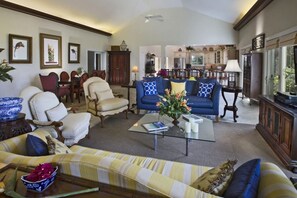 A spacious living room with a sofa, armchairs, and a coffee table. There is a dining area with chairs and a table, and a kitchen in the background. - Exquisite, private villa, centrally located and close to world-famous Magen`s Bay! (St. Thomas)
