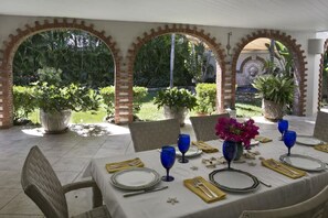 An outdoor dining area with brick arches, potted plants, and a table set for a meal. - Exquisite, private villa, centrally located and close to world-famous Magen`s Bay! (St. Thomas)
