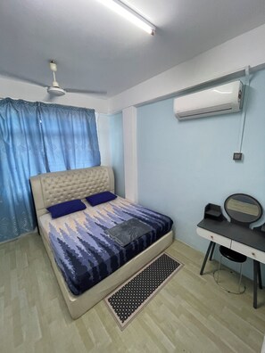 A bedroom with a bed, a desk, a chair, an air conditioner, and a ceiling fan.