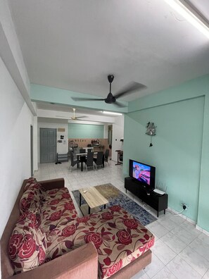 Ein Wohnzimmer mit einer Couch, einem Fernseher und einem Deckenventilator.