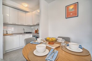 A modern kitchen with white cabinets, a dining table set with white bowls, glasses, and cutlery. - Spacious apartment with parking and big balcony, 4 min walk to beach (Split)