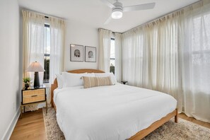Een slaapkamer met een groot bed, een nachtkastje met een lamp en twee ingelijste foto's aan de muur.
