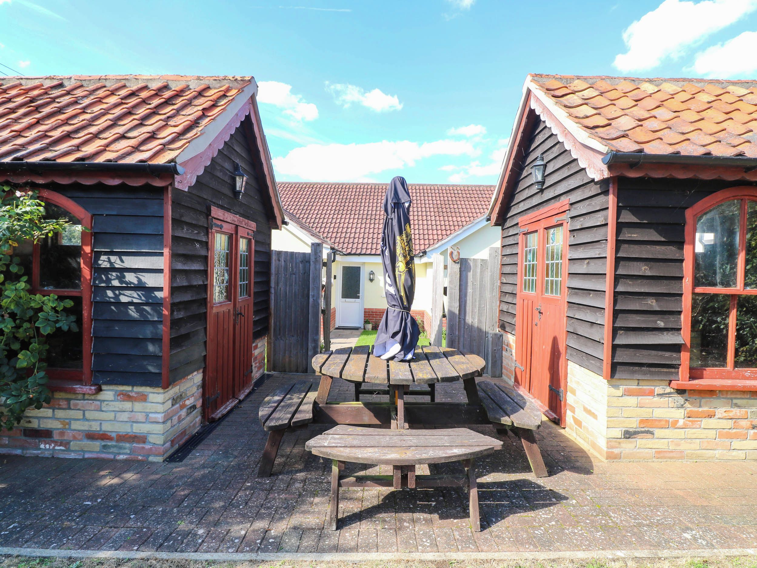A courtyard with wooden buildings, a central wooden bench, and a metal sculpture.