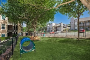 A playground with a slide and a bench, surrounded by a fence and trees. - Landing Amazing 2bd, Clubhouse, Gym (San Antonio)