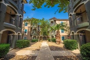 A multi-story residential building with balconies, a central pathway, and surrounding greenery. - Landing Amazing 2bd, Clubhouse, Gym (San Antonio)