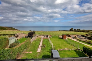 A coastal property with a grassy lawn, a brick pathway, and a small brick structure. - Ammonite Cottage, Sea Views (Port Mulgrave)