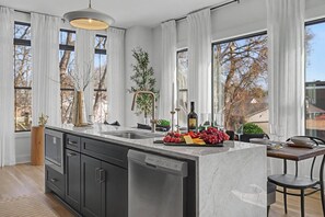 A modern kitchen with a central island, stainless steel appliances, and large windows. - The Highline | Rooftop Views | 5 Min to Downtown (Nashville)