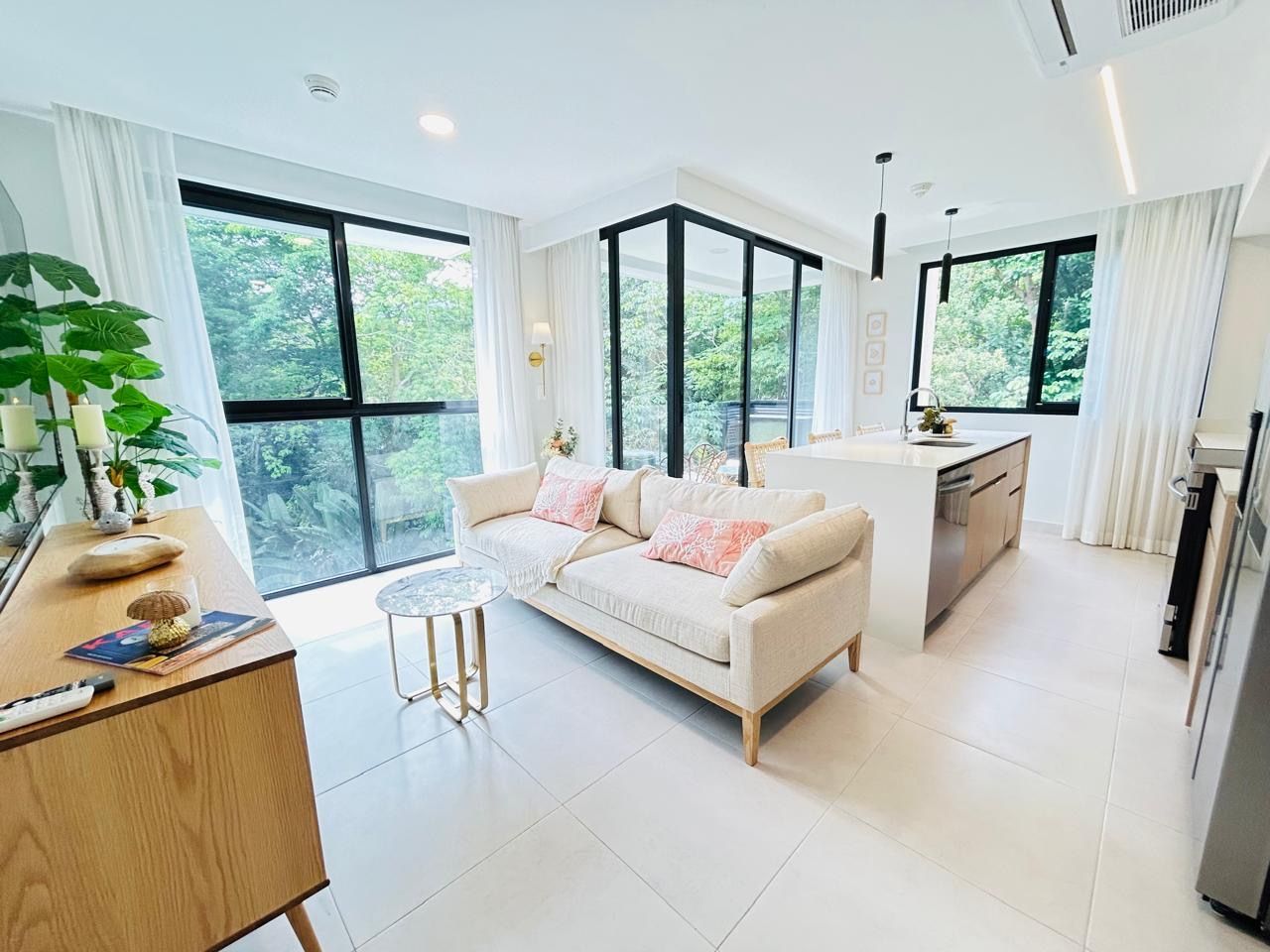 A modern living room with a sofa, a coffee table, and a kitchen area with a countertop and cabinets.