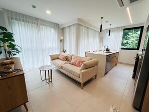 A modern kitchen with a sofa, dining table, and a large window. - Waves & Woods Hideaway (Jaco)