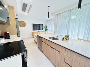 A modern kitchen with a central island, built-in appliances, and a large window with sheer curtains. - Waves & Woods Hideaway (Jaco)
