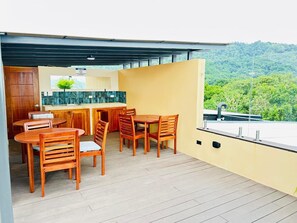 A modern outdoor dining area with wooden furniture and a kitchen counter. - Waves & Woods Hideaway (Jaco)