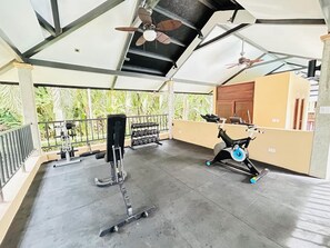 A covered gym area with exercise equipment, including a bench press and a stationary bike. - Waves & Woods Hideaway (Jaco)