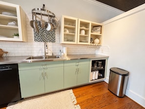 A kitchen with a dishwasher, a sink, and a trash bin.
