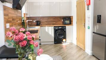 A modern kitchen with a built-in washing machine, a microwave, and a refrigerator.