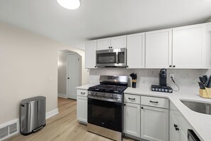 Eine moderne Küche mit weißen Schränken, Edelstahlgeräten und einem eingebauten Backofen.
