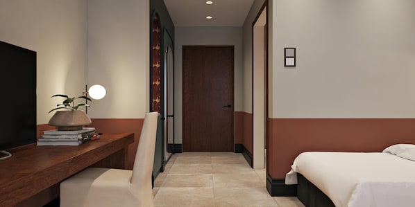 A hotel room with a desk, a chair, a bed, and a door.